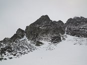 Ráno je zataženo, ale zatím nesněží. Cesta začíná v levém žlabu. Pokud vše půjde jak má, tím pravým bychom měli odpoledne scházet.